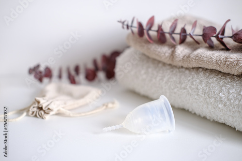 Fototapeta Naklejka Na Ścianę i Meble -  White menstrual cup close-up lies on a white background. Feminine and life background with eucalyptus.