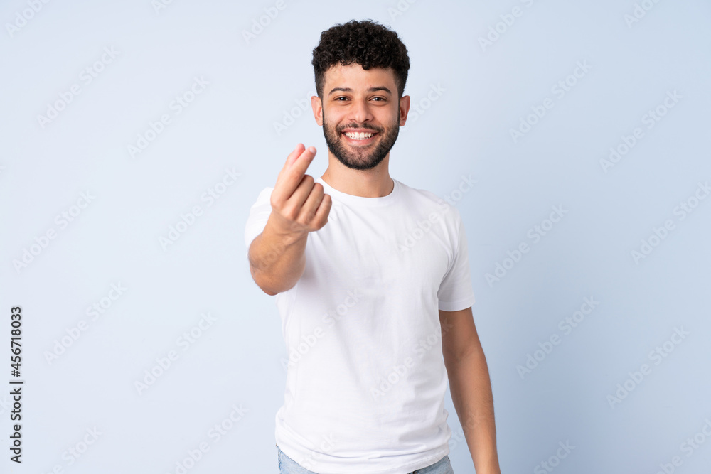 Young Moroccan man isolated on blue background making money gesture Young Moroccan man isolated on blue background making money gesture