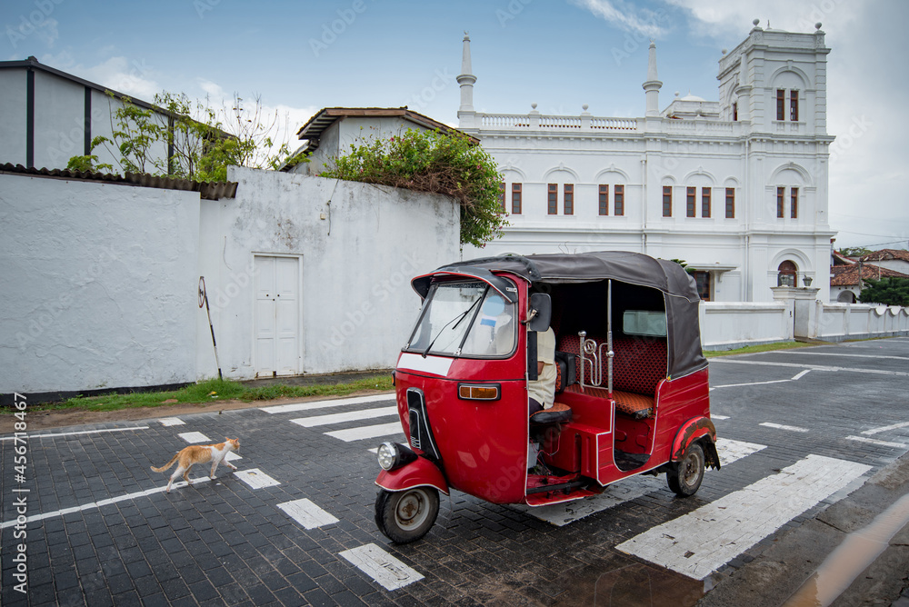 Red Tuk Tuk and little cat on the street near Galle Dutch Fort, one of travel attractions of Sri Lanka.