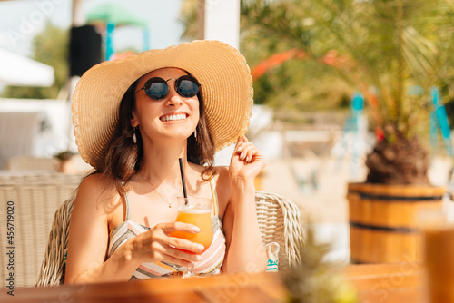 Young woman enjoys a cocktail outdoors on the beach on a sunny day.