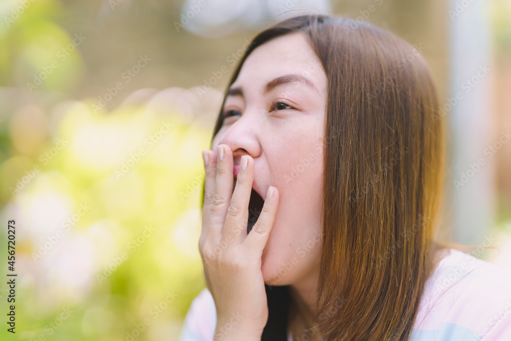 Thai woman covering her mouth while yawning. Thai woman covering her mouth while yawning.