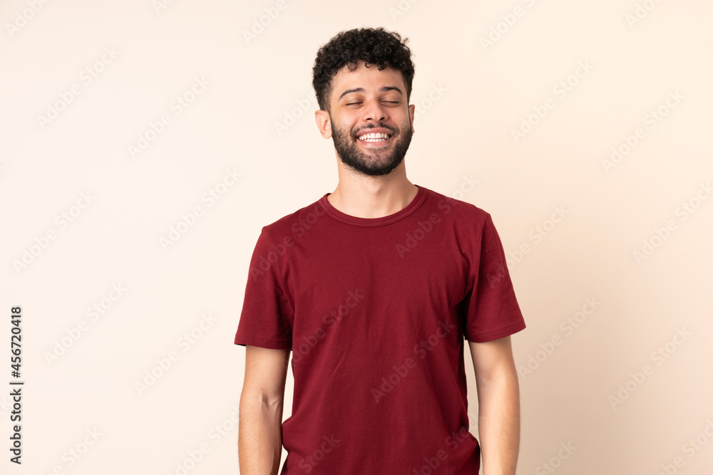 Obraz premium Young Moroccan man isolated on beige background laughing