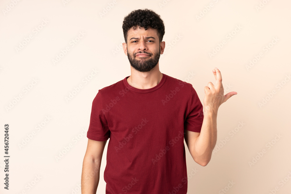 Young Moroccan man isolated on beige background with fingers crossing and wishing the best Young Moroccan man isolated on beige background with fingers crossing and wishing the best
