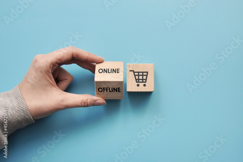 Wooden cubes with a picture of shopping baskets and the inscription: online and offline. Symbol for online or offline purchases