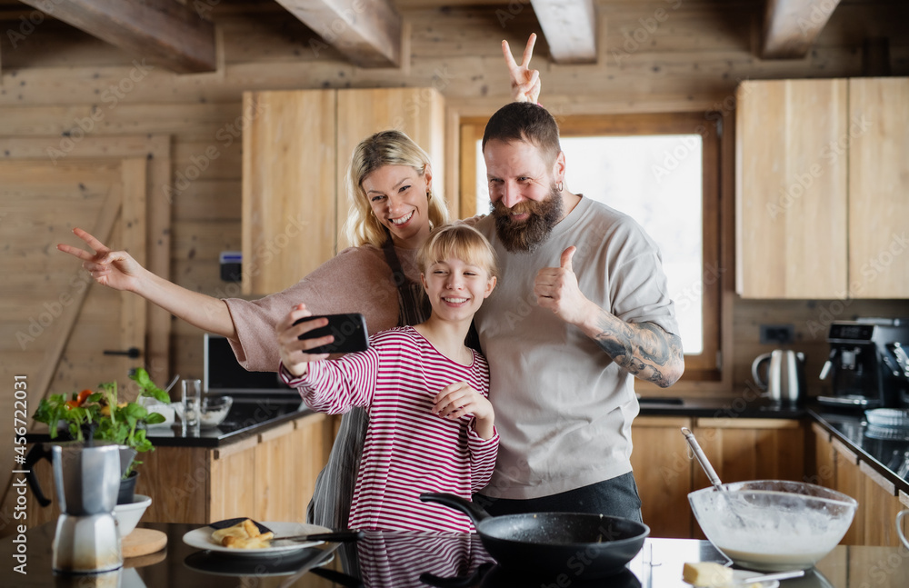 Family with small daughter taking selfie when cooking indoors, winter holiday in private apartment. Family with small daughter taking selfie when cooking indoors, winter holiday in private apartment.