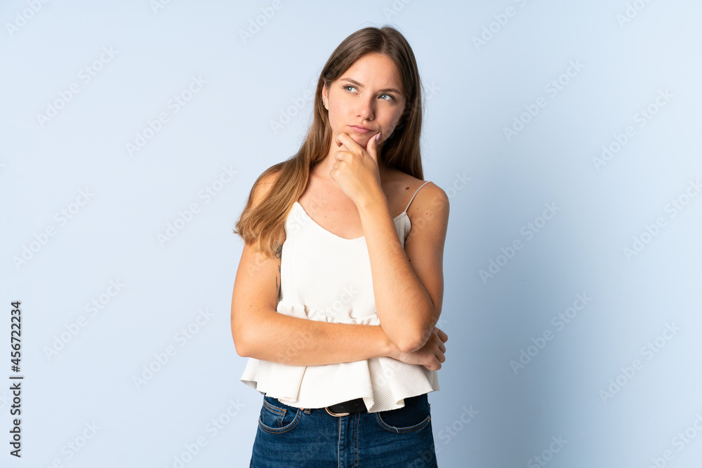 Young Lithuanian woman isolated on blue background having doubts Young Lithuanian woman isolated on blue background having doubts