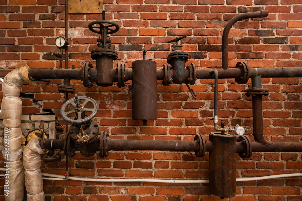 Old rusty water pipes with shutoff valves and sensors in an industrial
