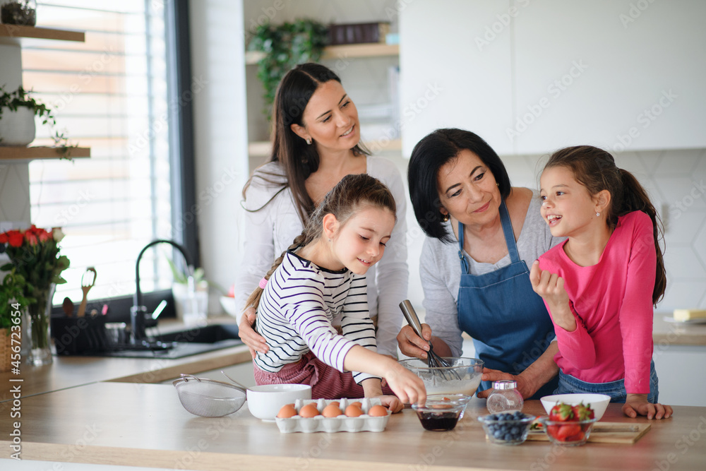 Happy small girls with mother and grandmother making pancake mixture indoors at home, cooking. Happy small girls with mother and grandmother making pancake mixture indoors at home, cooking.