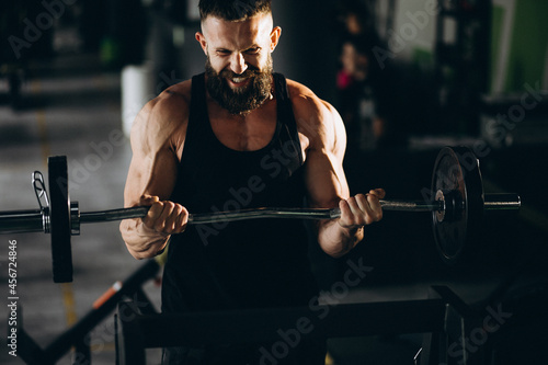 Handsome man bodybuilder doing workout at gym