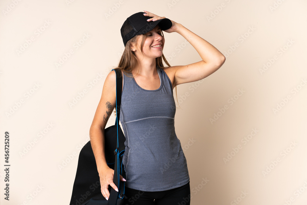 Young sport Lithuanian woman holding a sport bag isolated on beige background smiling a lot Young sport Lithuanian woman holding a sport bag isolated on beige background smiling a lot