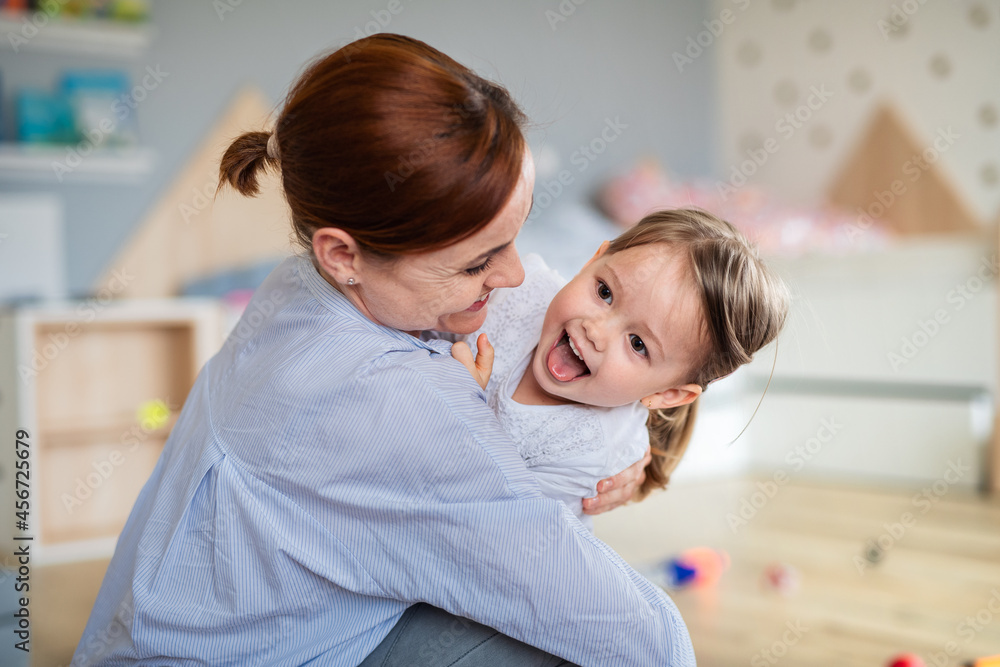 Happy mother with small daughter playing indoors in bedroom, laughing. Happy mother with small daughter playing indoors in bedroom, laughing.