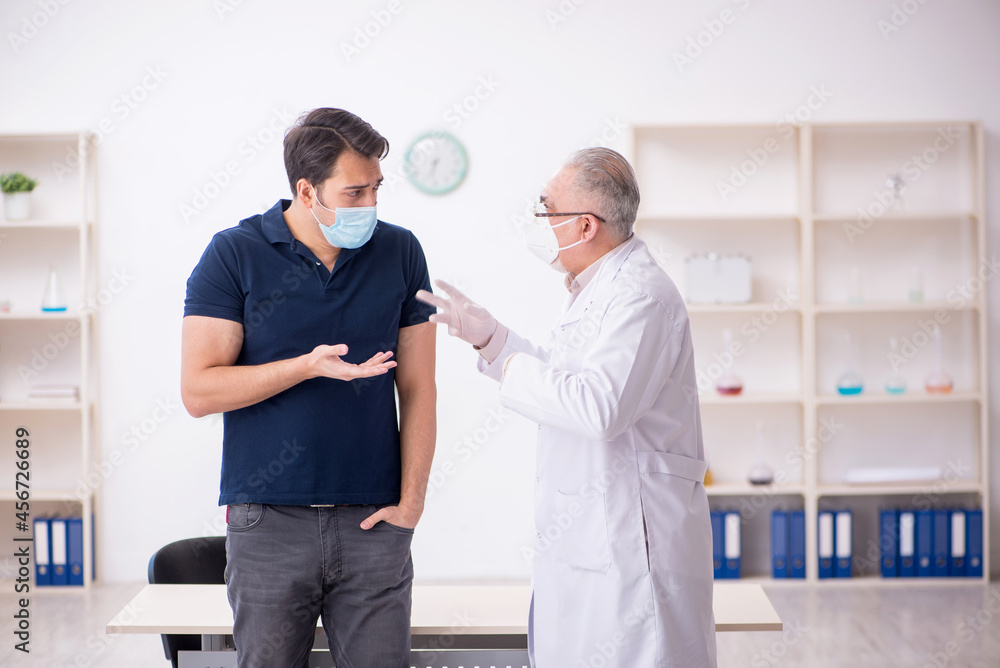 Fototapeta premium Young male patient visiting old male doctor during pandemic