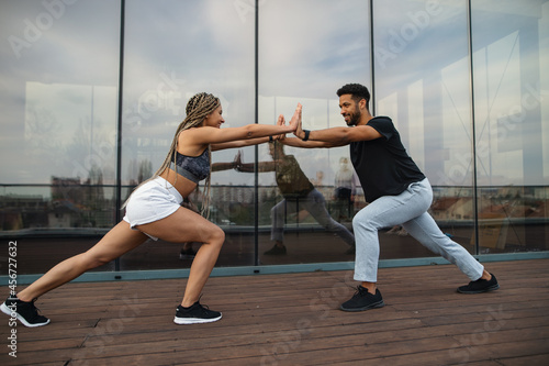 Young couple doing exercise workout outdoors on terrace, sport and healthy lifestyle concept.