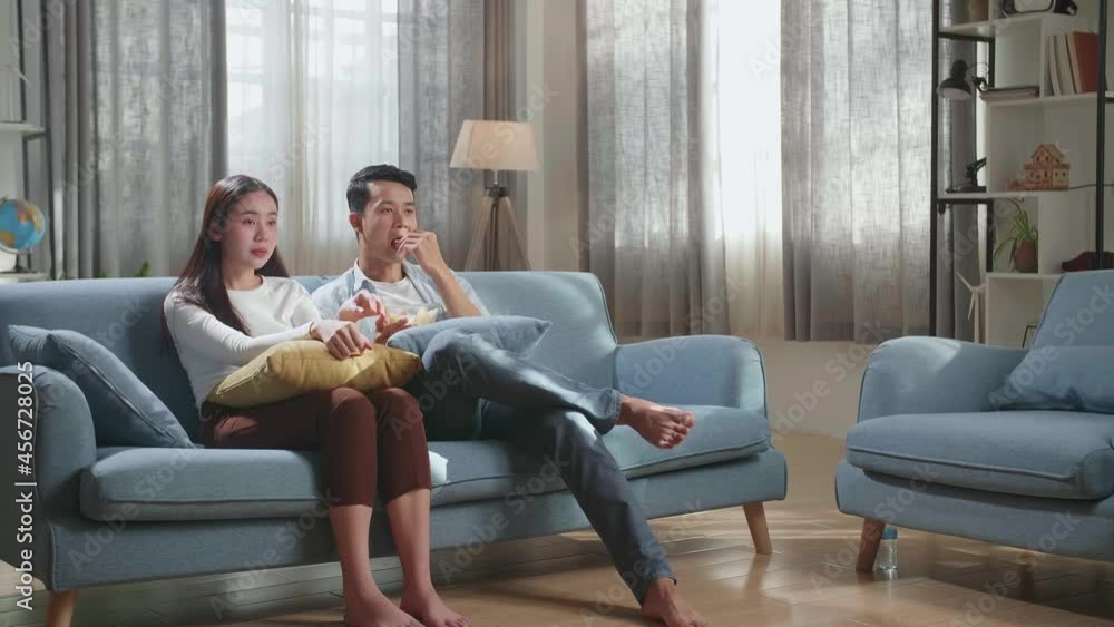 Young Asian Couple Eating Potato Chips And Watching Tv On Couch In Living Room
Young Asian Couple Eating Potato Chips And Watching Tv On Couch In Living Room