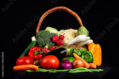 Verduras frescas en cesta de mimbre, fondo negro. 