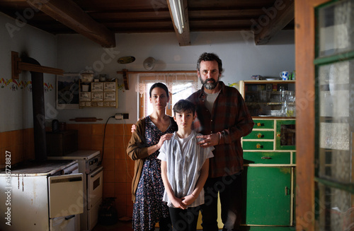 Portrait of poor mature couple with small daughter indoors at home, poverty concept.