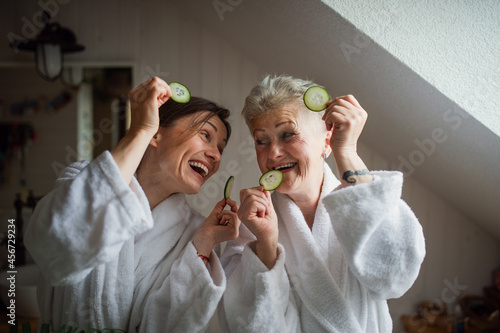 Happy senior mother in bathrobe with adult daughter indoors at home, selfcare concept. photo