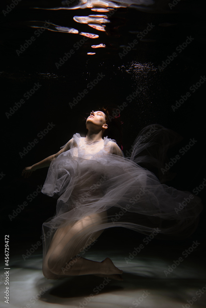 Photo of a beautiful girl with red hair posing in the water. She looks like a mermaid Photo of a beautiful girl with red hair posing in the water. She looks like a mermaid