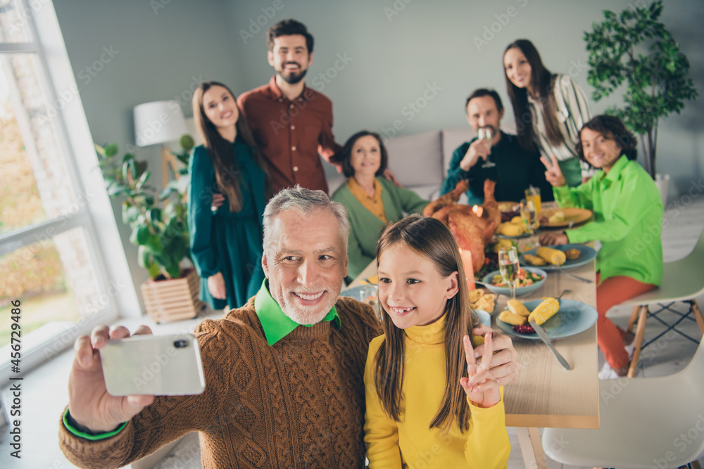 Photo of pretty cute family eating holiday turkey sitting table showing v-sign recording video modern device indoors house room