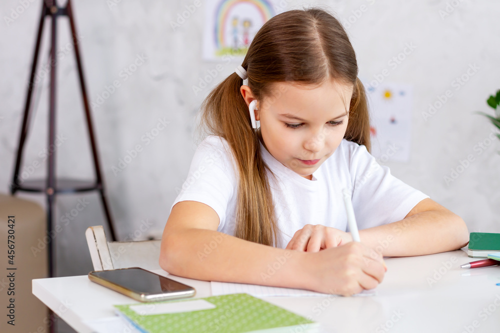 Remote school lessons. Child smiles studies and gets knowledge remotely. Little girl study online at home does homework. Distance learning education. Quarantine and Social distancing concept. Remote school lessons. Child smiles studies and gets knowledge remotely. Little girl study online at home does homework. Distance learning education. Quarantine and Social distancing concept.