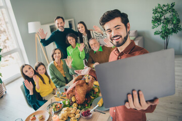 Photo of adorable funny family celebrating thanks giving day sitting table talking modern device smiling indoors room home