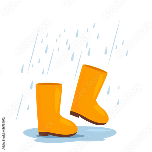 yellow rubber boots are walking in a puddle in the rain. autumn weather concept.