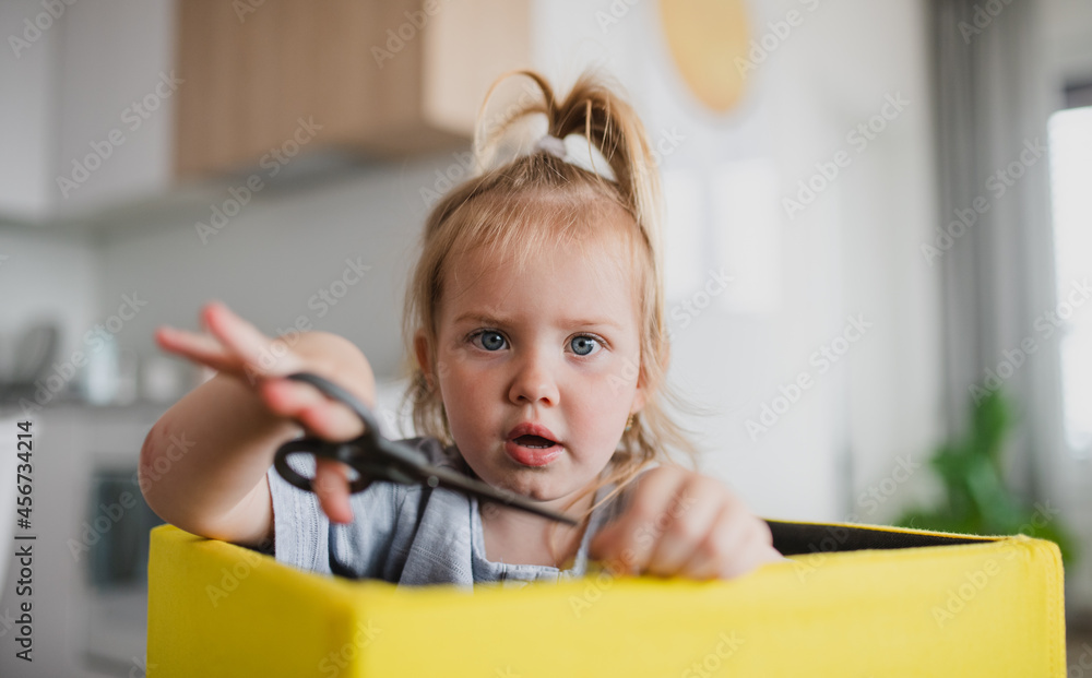 Portrait of little cauccasian girl using scissors indoors at home, looking at camera. Portrait of little cauccasian girl using scissors indoors at home, looking at camera.
