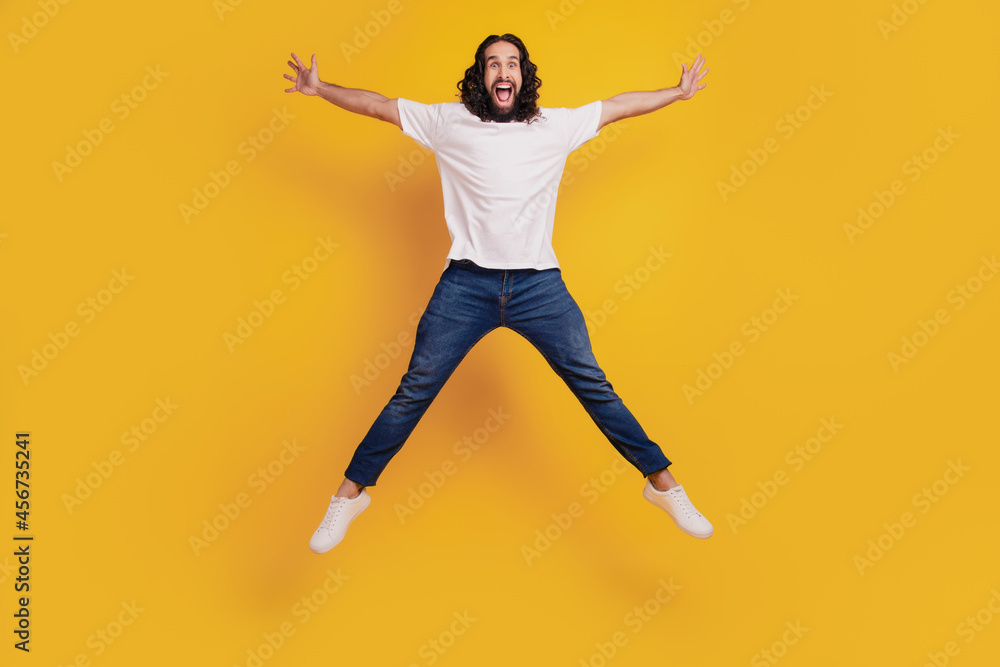 Portrait of funky sportive positive guy jump make star shape on yellow background Portrait of funky sportive positive guy jump make star shape on yellow background
