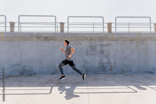 Young man running outdoors at noon