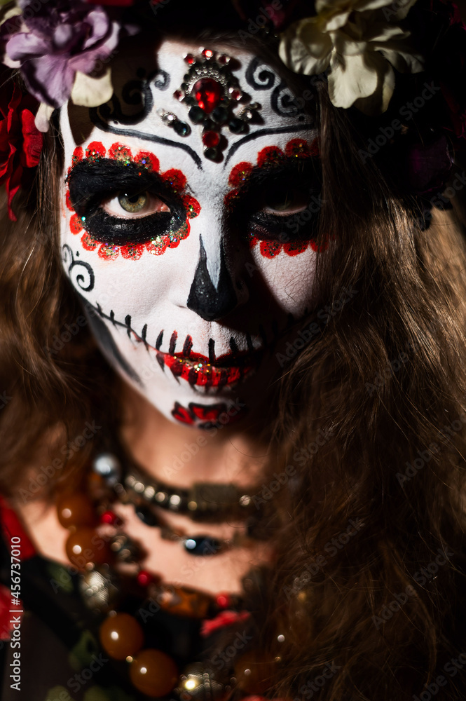 Woman in santa muerte makeup on a black background. Girl wearing traditional mexican holy death costume for halloween.