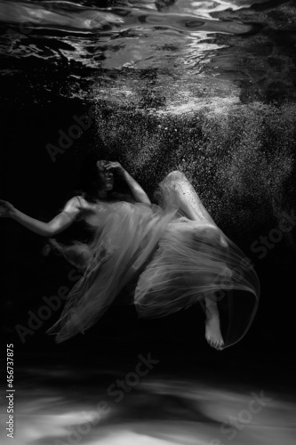 Black and white photographs where a beautiful girl poses in the water. She looks like a mythical mermaid