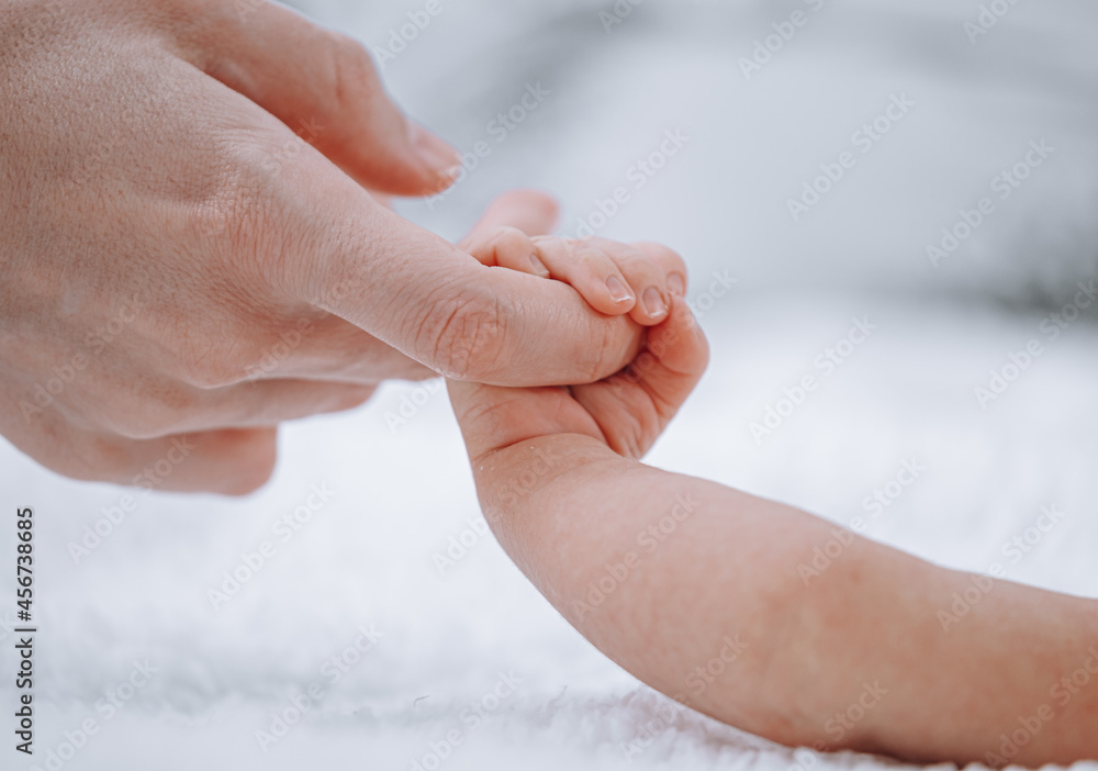 mom holds newborn baby by the hand