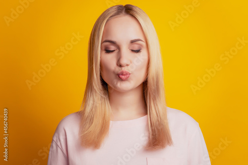 Portrait of dreamy inspired coquettish lady close eyes blow air kiss on yellow background © Tetiana
