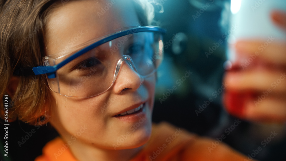 Smart Young Boy in Safety Goggles Mixes Chemicals in Beakers at Home. Teenager Conducting Educational Science Hobby Experiments, Doing Interesting Biology Homework in His Room. Close Up Portrait. Smart Young Boy in Safety Goggles Mixes Chemicals in Beakers at Home. Teenager Conducting Educational Science Hobby Experiments, Doing Interesting Biology Homework in His Room. Close Up Portrait.