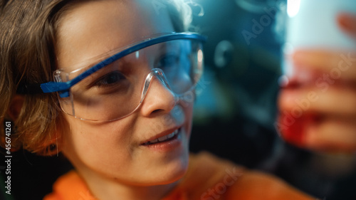 Smart Young Boy in Safety Goggles Mixes Chemicals in Beakers at Home. Teenager Conducting Educational Science Hobby Experiments, Doing Interesting Biology Homework in His Room. Close Up Portrait.