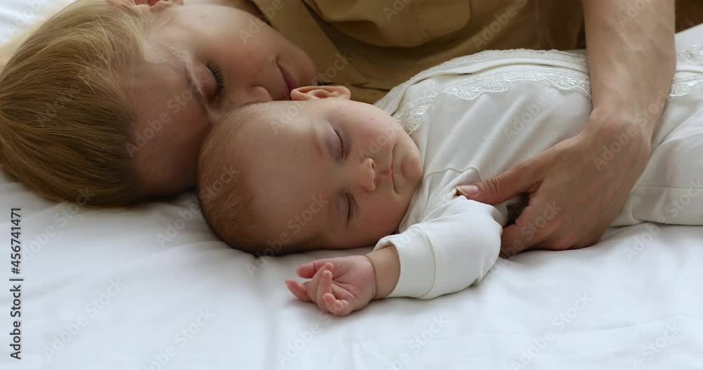 Loving mother hugging newborn, family sleeping together lying on comfortable fresh bedsheets, cosy bed, close up. Relaxation of parent and infant, co-sleeping, fatigue relief, healthy day nap concept Loving mother hugging newborn, family sleeping together lying on comfortable fresh bedsheets, cosy bed, close up. Relaxation of parent and infant, co-sleeping, fatigue relief, healthy day nap concept