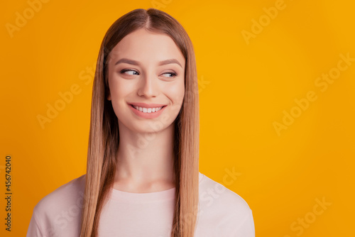 Portrait of dreamy positive lady look side empty space beaming white smile on yellow background