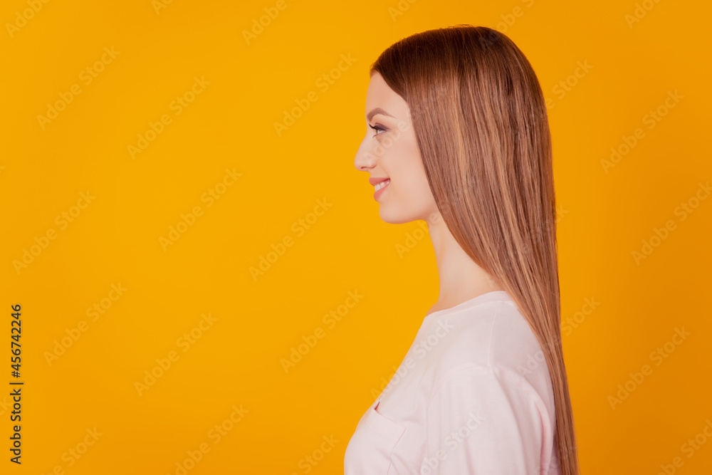 Profile portrait of positive gorgeous lady look blank space beaming smile on yellow background Profile portrait of positive gorgeous lady look blank space beaming smile on yellow background