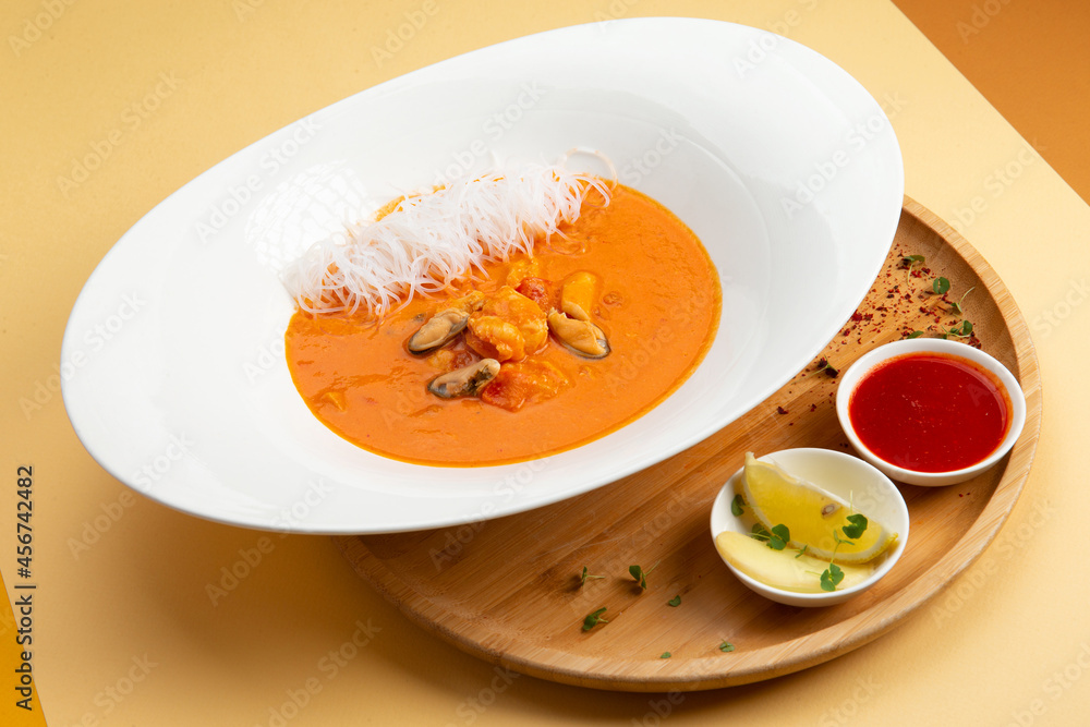 Traditional soup tom yam. In a plate on a light background. Traditional soup tom yam. In a plate on a light background.