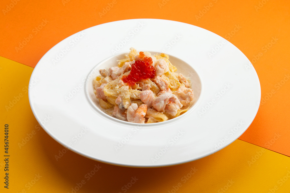 Pasta with seafood and red caviar. In a plate on a colored background. Pasta with seafood and red caviar. In a plate on a colored background.