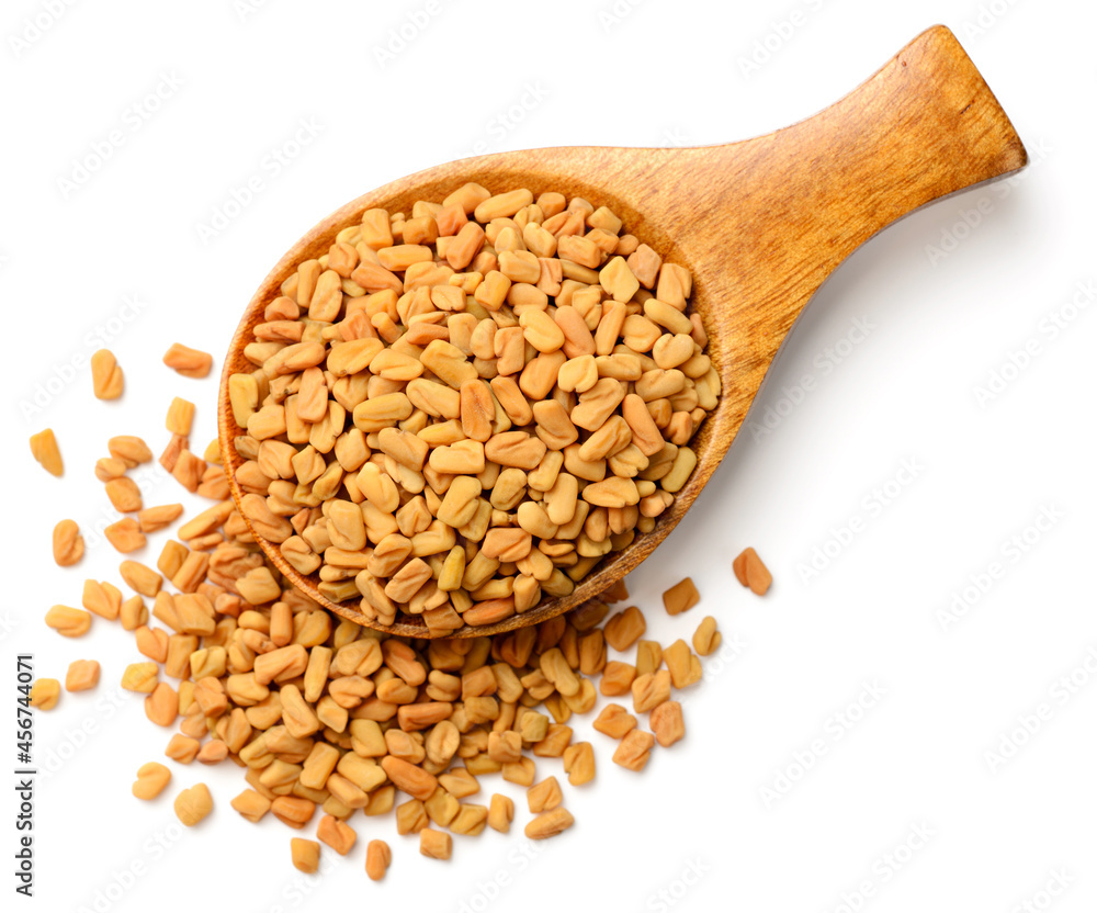 fenugreek seeds in the wooden spoon, isolated on the white background, top view fenugreek seeds in the wooden spoon, isolated on the white background, top view