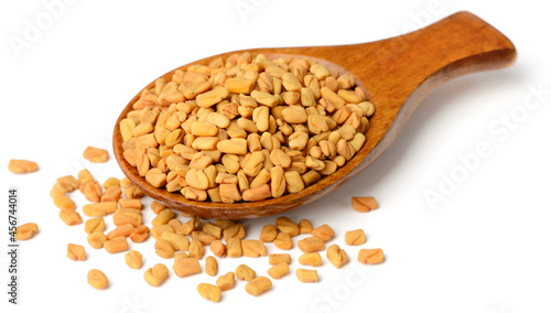 fenugreek seeds in the wooden spoon, isolated on the white background photo