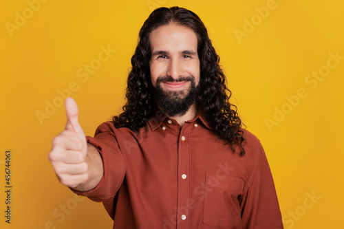 Portrait of reliable guy raise hand show thumb up on yellow background