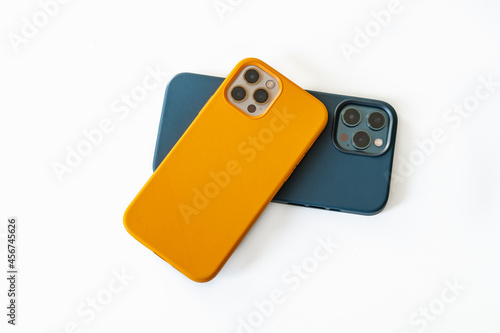 Modern mobile phones in blue and yellow leather cases on a white background. Modern smartphones with triple lens cameras