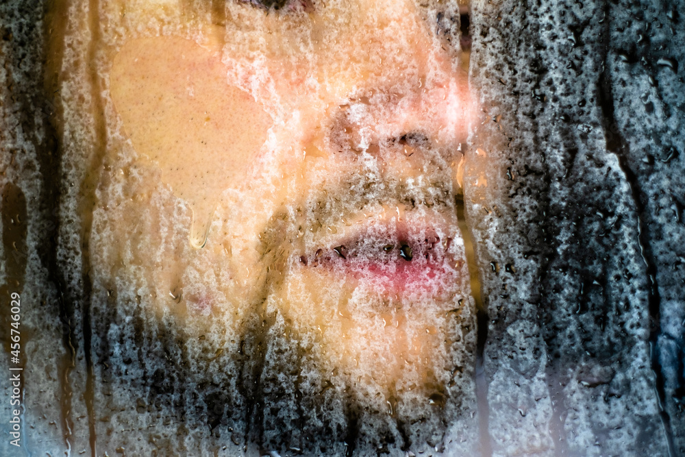 a bearded man in glasses and a white shirt in the shower stall