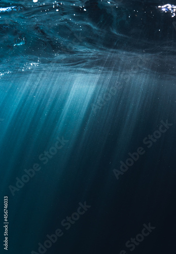 Sun rays of lights underwater in to blue clear ocean and bubbles