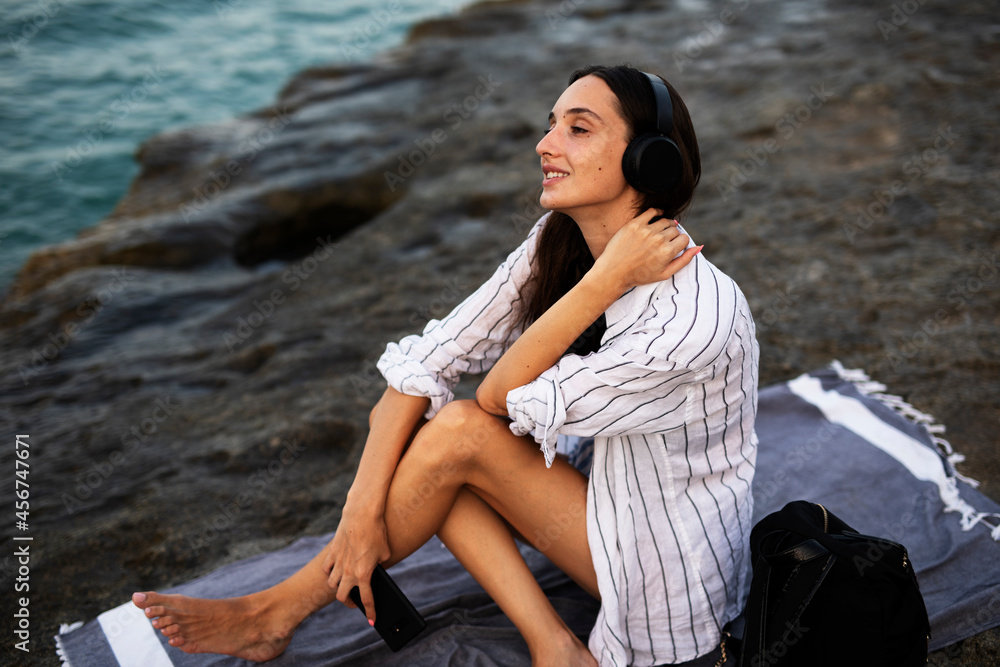 Happy young woman relaxing on the sandy beach. Beautiful woman listening the music Happy young woman relaxing on the sandy beach. Beautiful woman listening the music