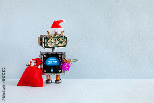 New Year Christmas card template. Toy robot Santa Claus with a traditional red hat, a big bag of holiday gifts, wishes a Happy New Year. Empty space for text on a gray background.