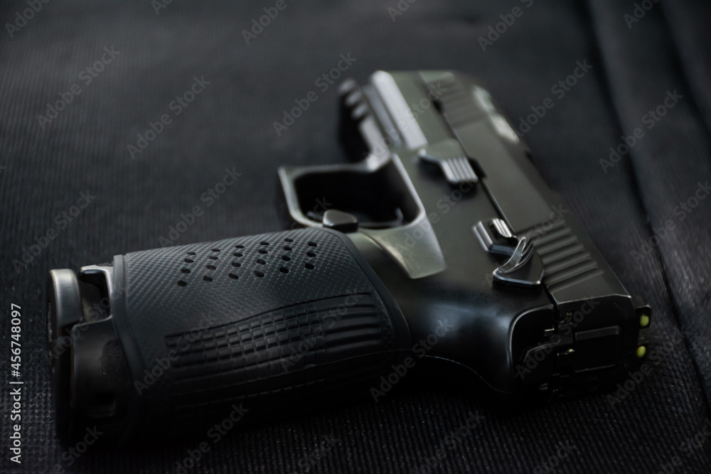 Automatic black 9mm pistol on black leather table. Soft and selective focus specific on gun. Automatic black 9mm pistol on black leather table. Soft and selective focus specific on gun.
