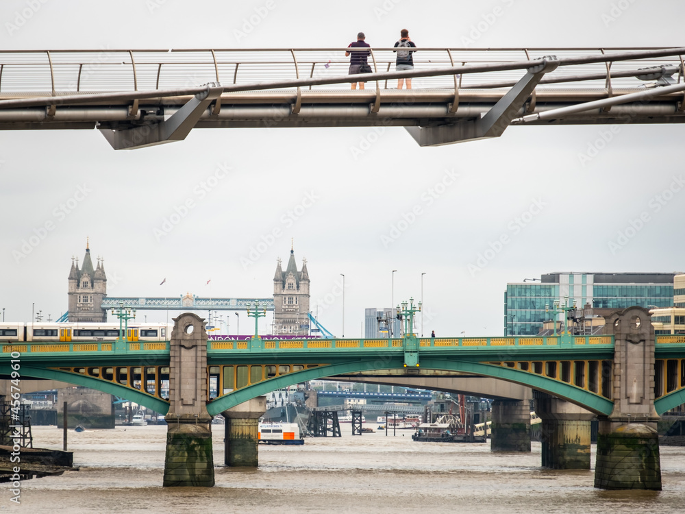 London scene over the River Thames with two people taking in the view of Tower Bridge from Millennium Bridge